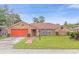 Brick ranch home with a large front yard and orange garage door at 897 Vicksburg St, Deltona, FL 32725