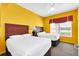 Two twin beds in a bright room with yellow walls at 8112 Poinciana Blvd # 1305, Orlando, FL 32821