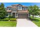 Two-story home with a modern facade, three-car garage and manicured lawn at 9101 El Caro Ln, Davenport, FL 33896
