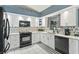 Modern kitchen with white cabinets, black appliances, and quartz countertops at 636 Koala Ct, Poinciana, FL 34759