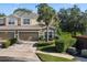 Tan two-story townhome with two-car garage, lush landscaping, and a palm tree at 400 Harbor Winds Ct, Winter Springs, FL 32708