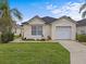 Single-story house with a beige exterior, a white garage door, and a well-manicured lawn at 2977 Kokomo Loop, Haines City, FL 33844