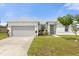 White one-story house with gray garage door and landscaping at 325 Daffodil Ln, Kissimmee, FL 34759