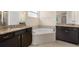 Bathroom with granite countertops, corner soaking tub, and dark cabinets at 4814 Terra Sole Pl, St Cloud, FL 34771