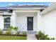 Modern house entrance with dark gray door, white exterior, and solar panels on the roof at 1302 Belmar Ter, Deltona, FL 32725