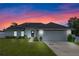 Modern home exterior at sunset with solar panels and a two-car garage at 1302 Belmar Ter, Deltona, FL 32725