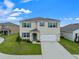 Two-story house with a two-car garage, landscaping, and a teal front door at 821 Sun Burst Rd, Winter Haven, FL 33880