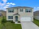 Two-story house with a two-car garage, landscaping, and a teal front door at 821 Sun Burst Rd, Winter Haven, FL 33880