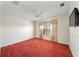 Bright bedroom with red carpet, window with curtains and a ceiling fan at 16950 Se 80Th Bellavista Cir, The Villages, FL 32162