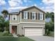 Two story home with two tone exterior, two car garage, and red door at 1955 Hemingway Cir, Groveland, FL 34736