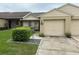 Front view of a tan brick home with a two car garage and landscaping at 5027 Se 109Th Pl, Belleview, FL 34420