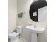 Small bathroom with pedestal sink and round mirror at 1820 Holden Ridge Ln, Clermont, FL 34715