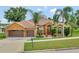 Attractive one-story home with a two-car garage, landscaping, and palm trees at 12941 Colonnade Cir, Clermont, FL 34711