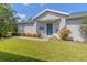 House exterior showcasing a light gray color scheme, teal front door, and lush landscaping at 151 Bell Tower W Xing, Poinciana, FL 34759