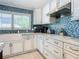 Modern kitchen with white cabinets, stainless steel appliances, and a blue mosaic backsplash at 2903 Hill St, New Smyrna Beach, FL 32169