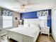 Bedroom with white bed frame, blue accent wall, and full-length mirror at 1410 Wexford Way, Davenport, FL 33896