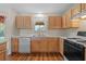Kitchen with double sink, light wood cabinets, and black stove at 17394 Se 74Th Seabrook Ct, The Villages, FL 32162