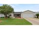 Tan one-story house with two-car garage, screened porch, and landscaping at 17394 Se 74Th Seabrook Ct, The Villages, FL 32162