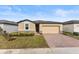 Tan house with dark brown roof, brick driveway and landscaping at 3206 Viceroy Ct, Poinciana, FL 34759