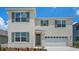Two-story home with light beige siding, green shutters, and a two-car garage at 3540 Broadwing Blvd, Poinciana, FL 34759