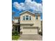 Two story home with light beige exterior, three car garage, and landscaping at 1075 Trappers Trail Loop, Davenport, FL 33896