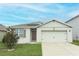 Tan house with brown accents, solar panels, and a two-car garage at 277 Ludisia Loop, Davenport, FL 33837
