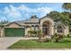 Tan one-story house with green garage door and landscaped yard at 16208 Magnolia Hill St, Clermont, FL 34714