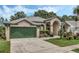 Tan one-story house with green garage door and landscaped yard at 16208 Magnolia Hill St, Clermont, FL 34714