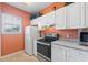 Kitchen with white cabinets, stainless steel appliances, and orange walls at 720 Celebration Ave # 220, Celebration, FL 34747