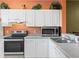 Kitchen with white cabinets, stainless steel appliances, and orange walls at 720 Celebration Ave # 220, Celebration, FL 34747