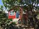 Red house exterior partially obscured by trees and landscaping at 10 Mccarthy Ave, Frostproof, FL 33843