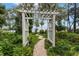 Brick pathway leads through a garden to a white arbor overlooking a lake at 9164 Point Cypress Dr, Orlando, FL 32836