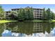 Building exterior with pond reflection, showcasing a three-story building with balconies at 9055 Treasure Trove Ln # 206, Kissimmee, FL 34747