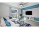 Living room with white sectional sofa, large TV, and blue accent wall at 4804 Memories Ln, Kissimmee, FL 34746