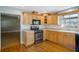 Kitchen with wood cabinets, black appliances, and hardwood floors at 5625 Chipola Cir, Orlando, FL 32839