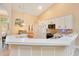 Open kitchen with white cabinets, a breakfast bar, and a view into the living area at 1434 Hidden Meadow Way, Apopka, FL 32712