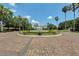 Community entrance with a fountain, lush landscaping, and palm trees at 2366 Prairie Dunes, Clermont, FL 34711