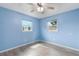 Light blue bedroom with wood-look floors, ceiling fan, and two windows at 926 Everett St, Lake Alfred, FL 33850