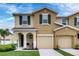 Two story tan house with dark shutters, two car garage, and front porch at 5116 Killarney Way, Kissimmee, FL 34746