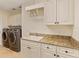 Bright laundry room with washer, dryer, and granite countertop at 11227 Macaw Ct, Windermere, FL 34786