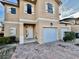 Front view of a two-story townhome featuring a white garage door at 1431 Pacific Rd, Poinciana, FL 34759