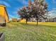 Green grassy backyard with mature trees and townhomes in the distance at 1431 Pacific Rd, Poinciana, FL 34759