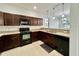 L-shaped kitchen with dark brown cabinets and granite countertops at 1431 Pacific Rd, Poinciana, FL 34759