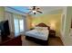 King-size bed in a bright bedroom with a ceiling fan, dresser, and ensuite bath at 8101 Resort Village Dr, Orlando, FL 32821