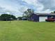 Purple house with solar panels, large yard, and outbuildings in the background at 4805 Hunting Lodge Dr, Saint Cloud, FL 34772