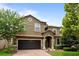 Two-story house with a dark brown garage door and landscaped lawn at 1414 Thunderbird Rd, Davenport, FL 33896