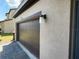 Attached garage with dark brown door and exterior light fixture at 226 Macaulays Cv, Haines City, FL 33844