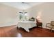 Comfortable bedroom with hardwood floors, featuring a queen-size bed and a sitting chair at 3499 Rockcliff Pl, Longwood, FL 32779