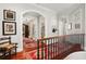Upper hallway with hardwood floors, arched doorways, and ornate railing at 1391 Richmond Rd, Winter Park, FL 32789
