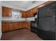Galley kitchen with wood cabinets, black appliances, and a window at 104 E Mcclendon St, Lady Lake, FL 32159